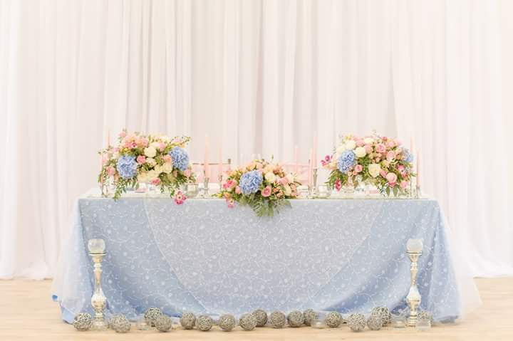 Decorated table with floral arrangements against a white curtain background